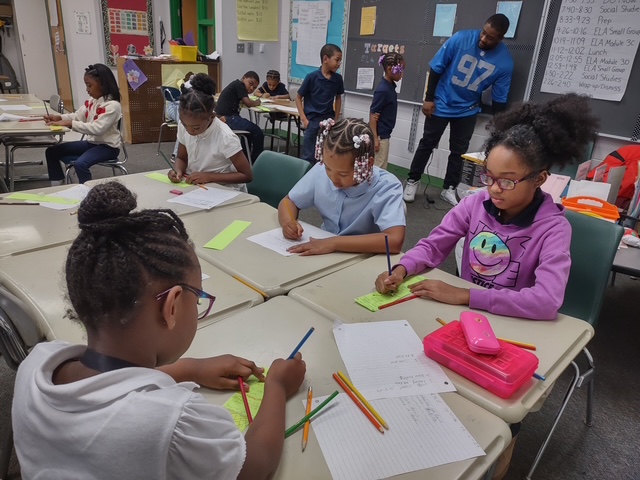  Students sitting at their desks using tools to dig for fossils